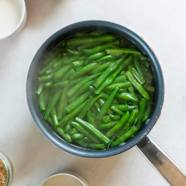 Green beans being blanched in boiling water in a pot.