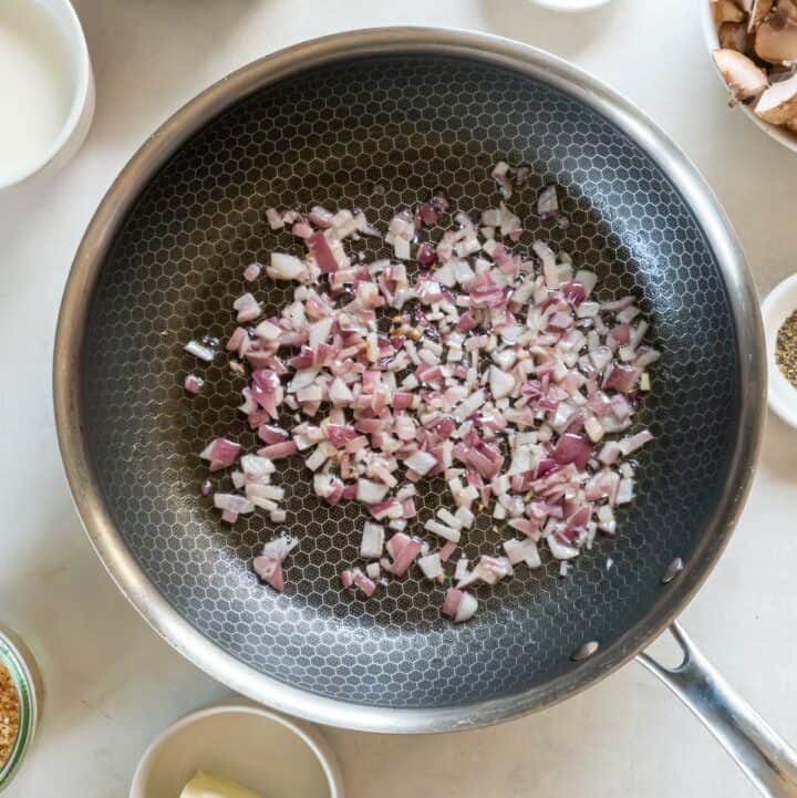 Onions being sauteed in a skillet.