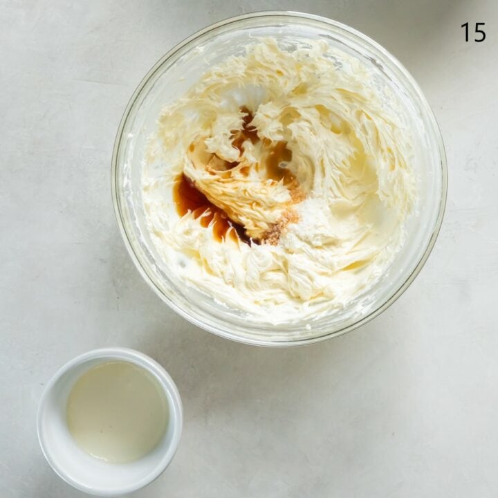 The vanilla and salt being mixed into the cream cheese mixture in a glass bowl. A separate bowl of cream sits next to it, waiting to be added.