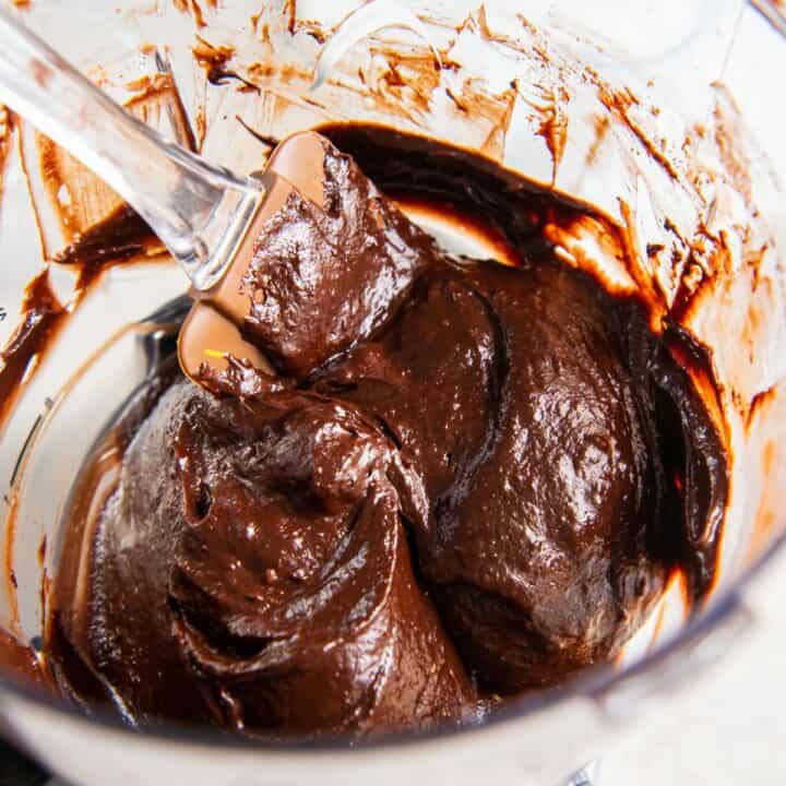 A spatula scrapping the avocado chocolate pudding out of the food processor.