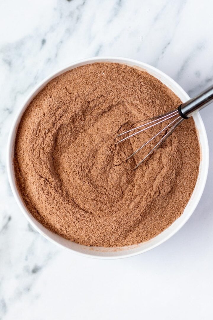 A bowl with all of the ingredients to make your keto hot chocolate mix being whisked together.